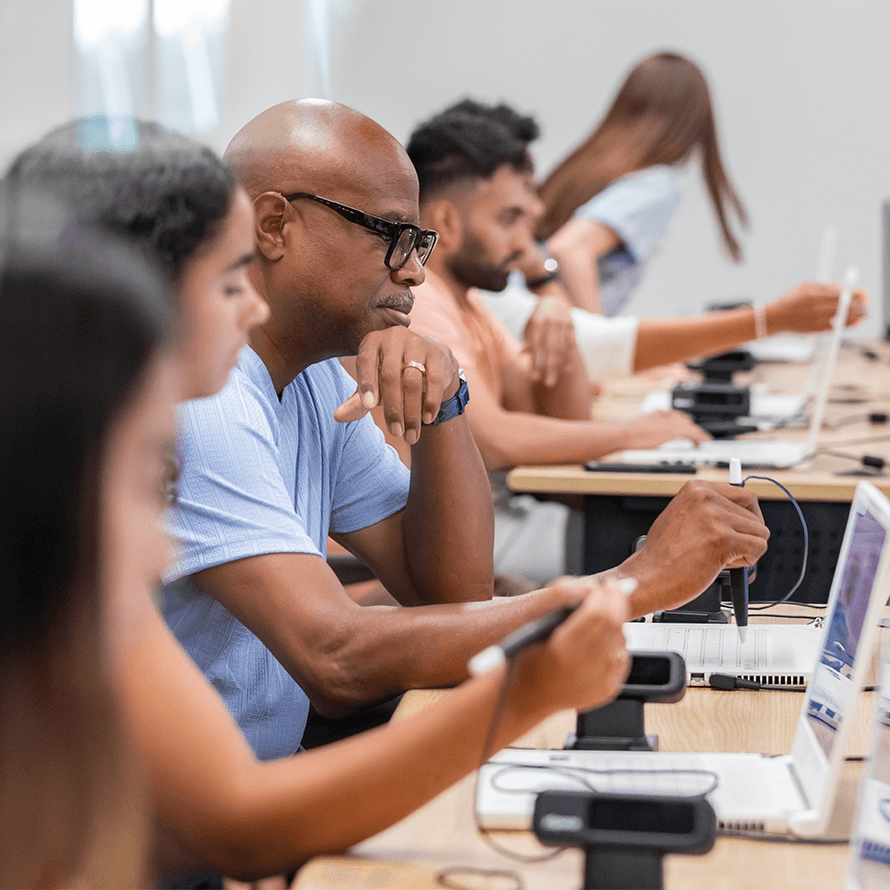 Row of Students at Desks Working at Laptops