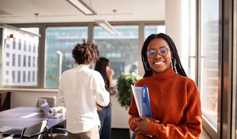 A Woman Smiling While Holding Papers in an Office
