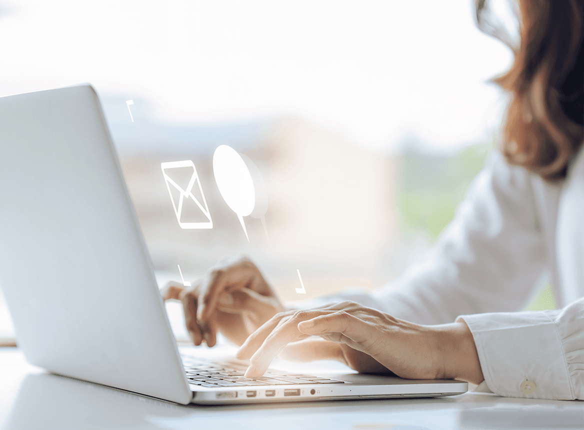 Person Typing on Laptop with Communication Icons Floating Above the Hands