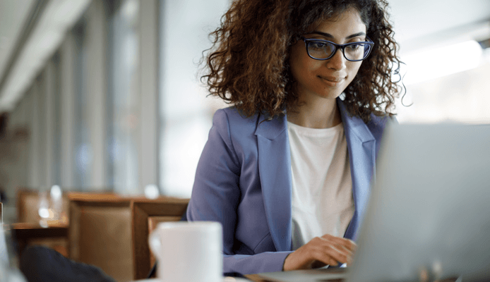 Woman With a Coffee Smiling at Laptop