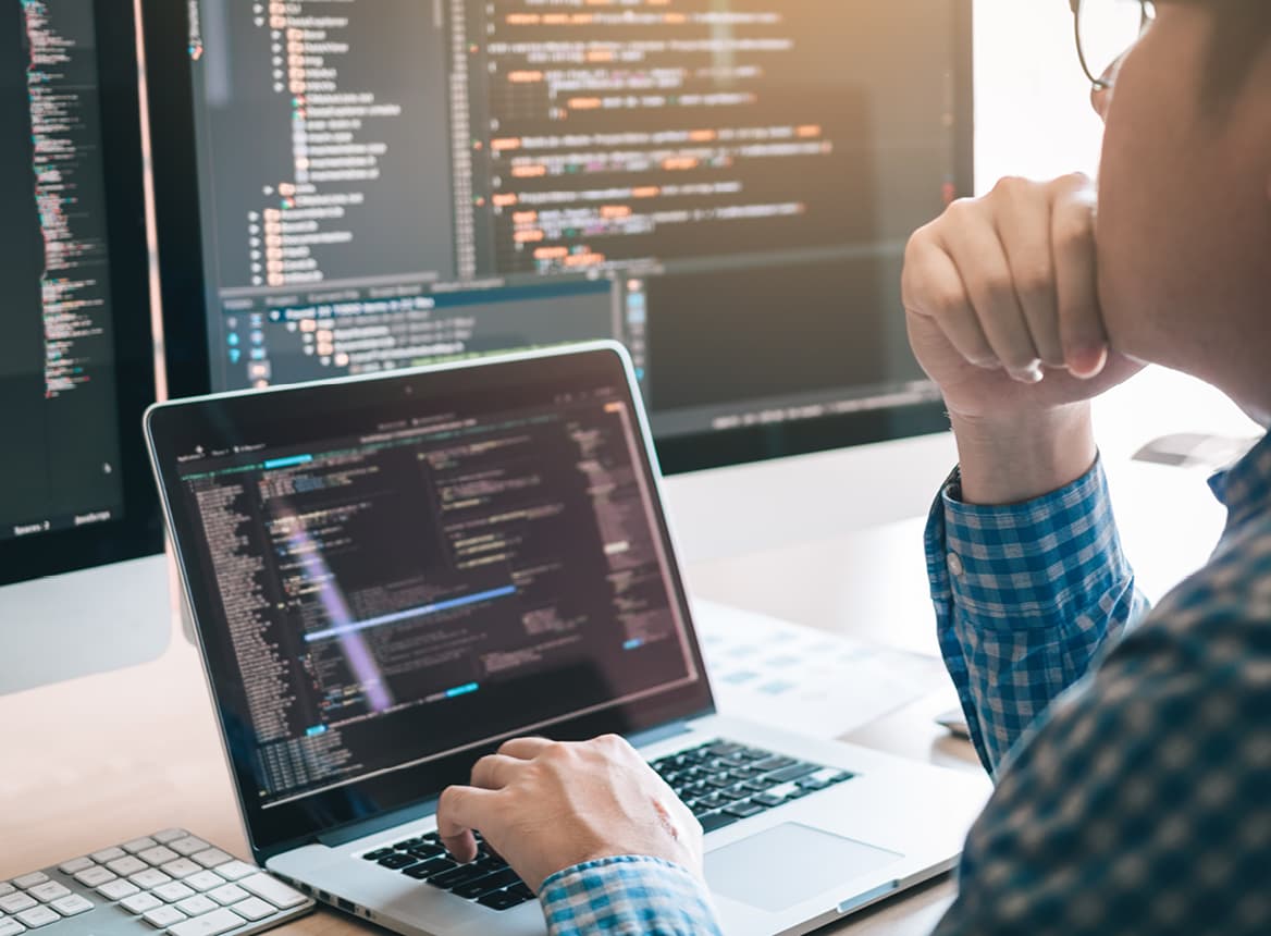 Close Up of Man Using a Computer With a Larger Monitor on His Desk