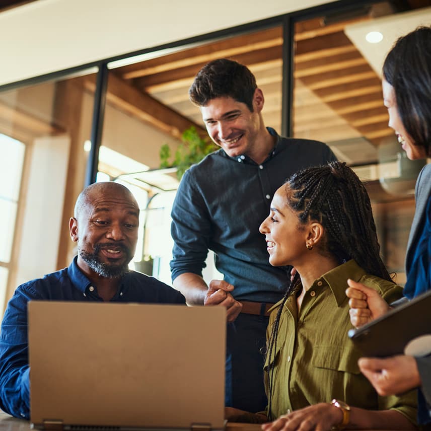 Four People Smiling While Looking at a Laptop