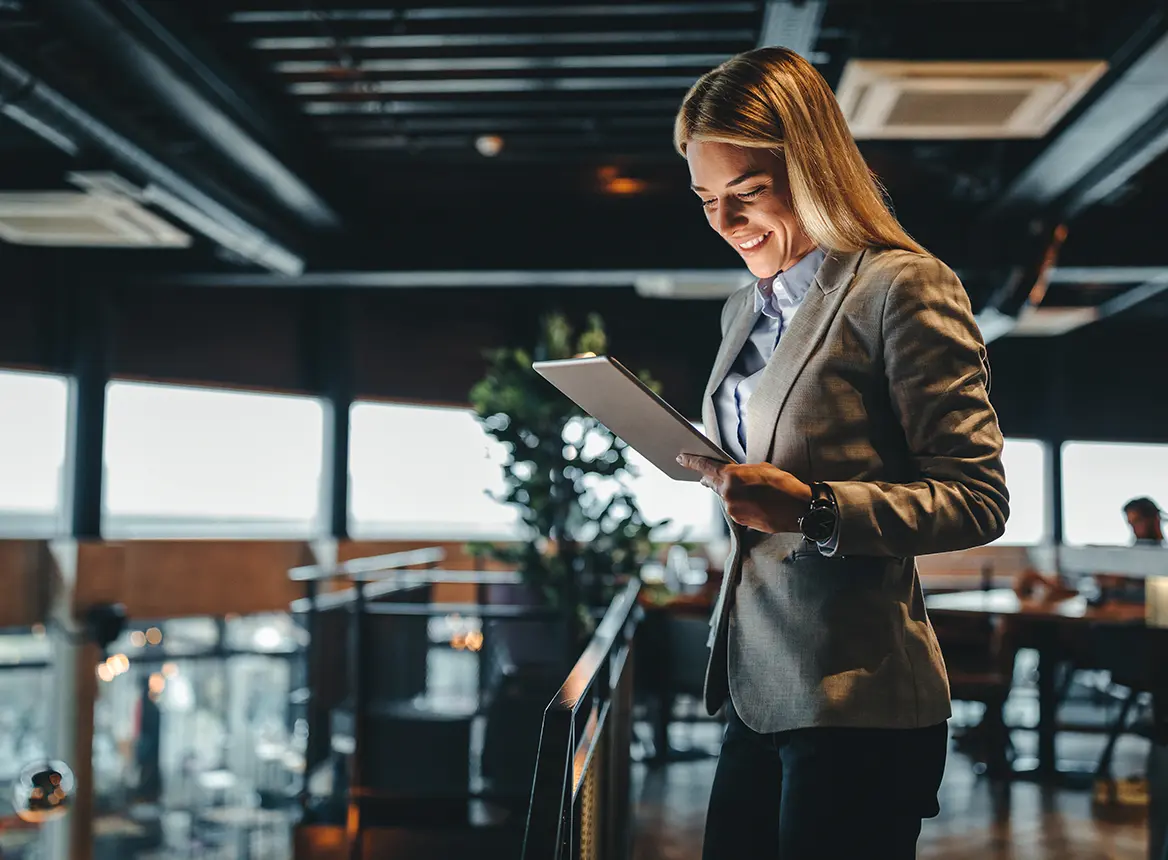 Blonde Woman Smiling and Looking at Tablet