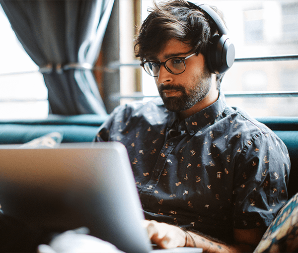 Man with Headphones Looking at Laptop