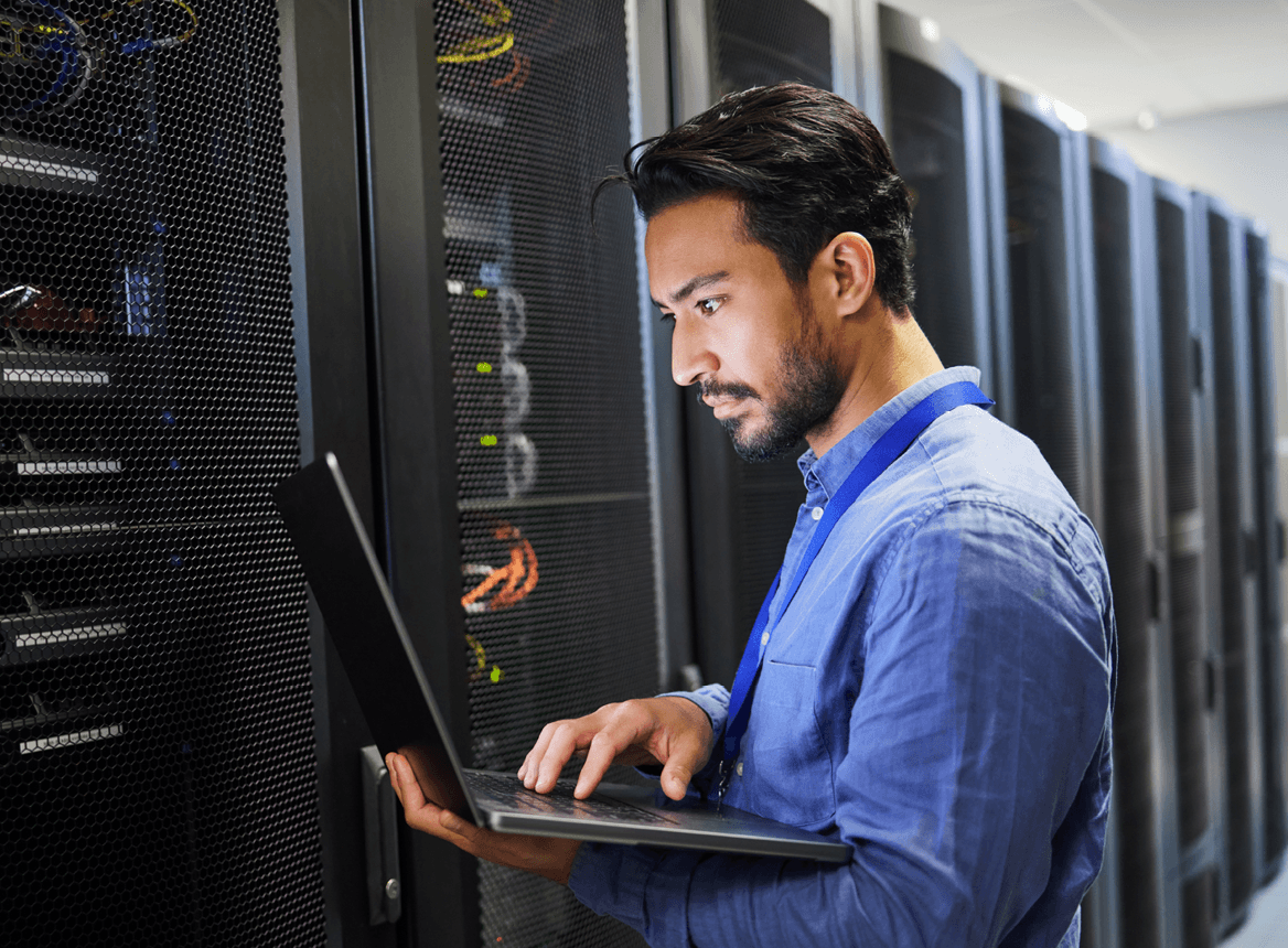 Person Looking at Laptop In Front of Servers