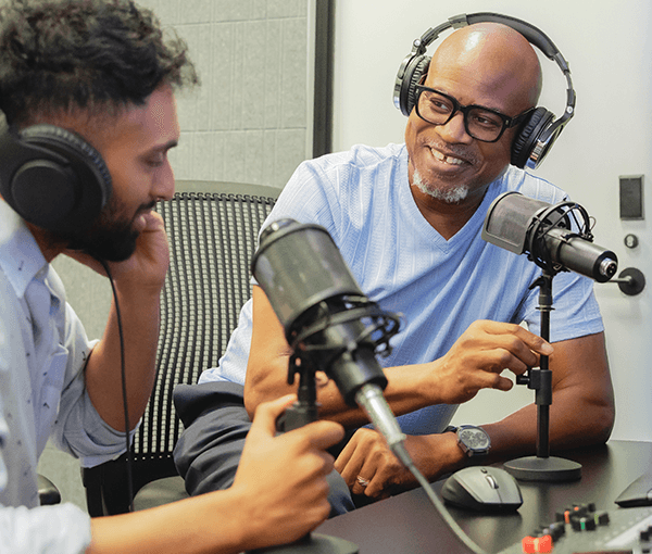 Two people smiling and talking into microphones